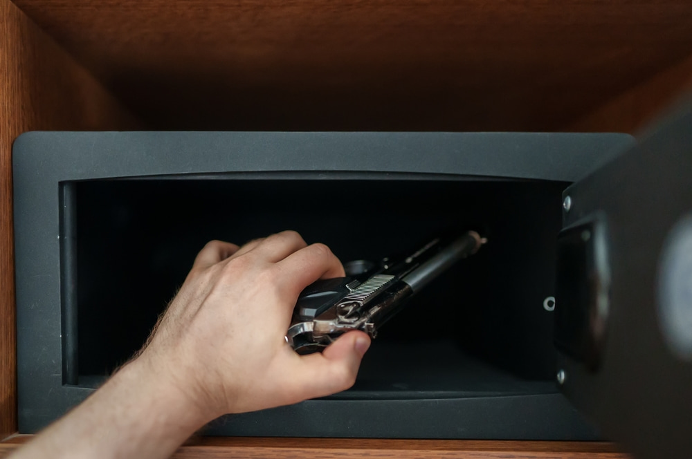 ผู้ชายกำลังเก็บปืนไว้ในตู้เซฟ